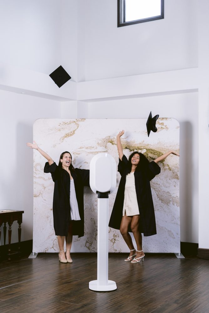 Graduates celebrating with caps in the air in front of The Missouri digital booth